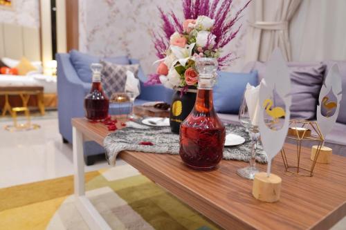 a table with two bottles and a vase of flowers at شقق سما الرفاع للشقق المخدومة in Al Kharj