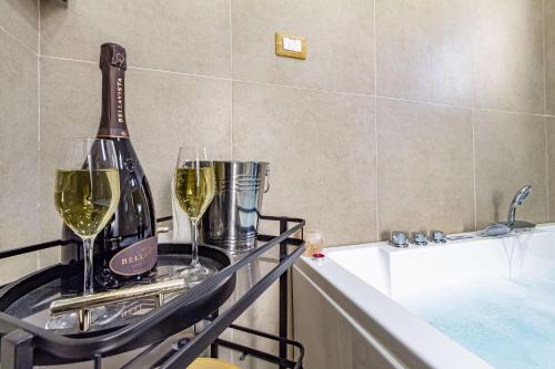 two glasses of wine on a tray next to a bath tub at Blanche Apartments in Porto Torres