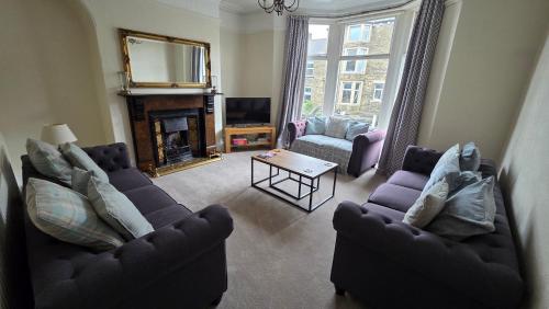 a living room with two couches and a fireplace at Westfield House - Characterful 7 bedroom townhouse in Skipton