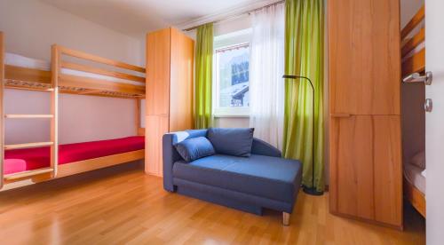 a bedroom with a blue chair and a bunk bed at Haus CKPK Lux in Sonnenalpe Nassfeld