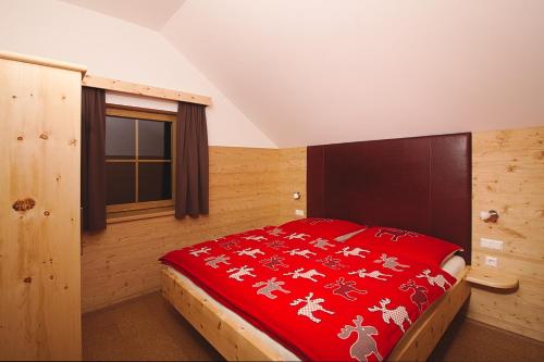 ein Schlafzimmer mit einem Bett mit einer roten Decke in der Unterkunft Bio Chalet "Sonne" in Weisspriach
