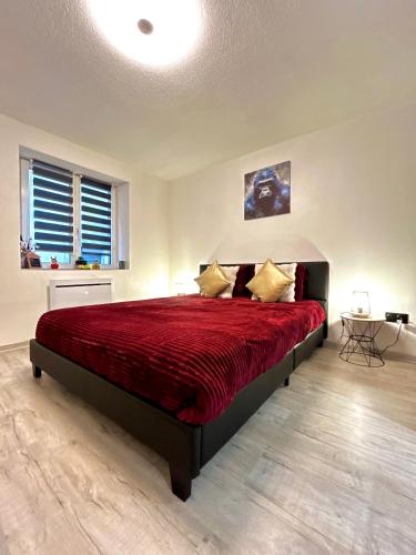 a bedroom with a large bed with a red bedspread at Au Cocon Alsacien in Wintzenheim
