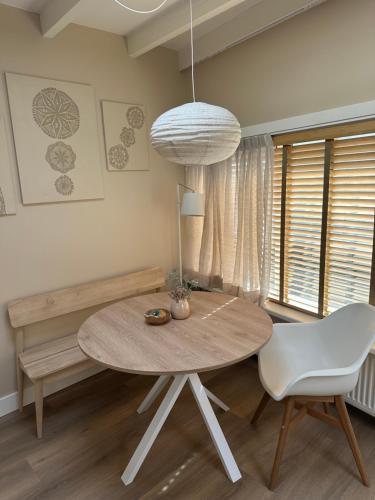 a dining room with a table and a white chair at Studio Oranje Nassau aan Zee in Zandvoort