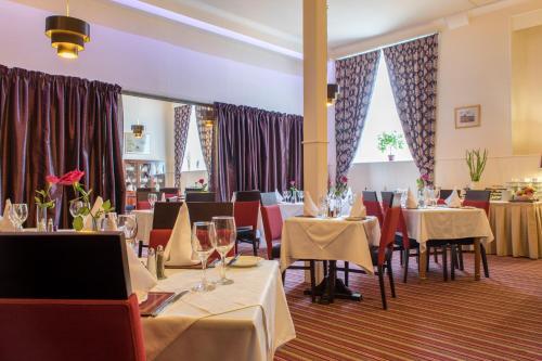 a dining room with tables and chairs and windows at Eskdale Hotel in Langholm
