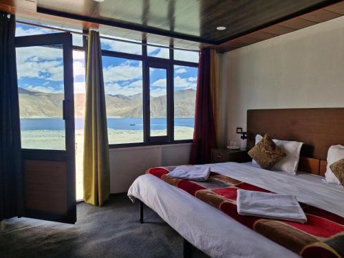 a bedroom with a bed and a large window at pangong rainbow cottage in Lukung