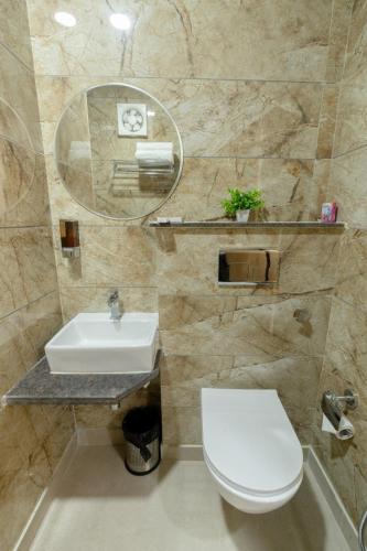 a bathroom with a sink and a toilet and a mirror at Hotel Ganga Stone in Rāiwāla