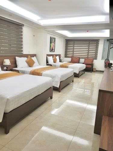 a room with three beds and a couch at Vũ Gia Hotel in Hanoi