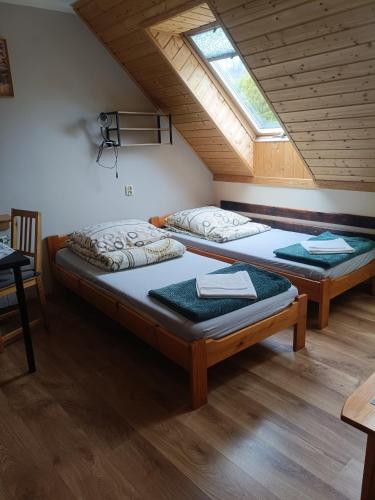 two beds in a attic room with a window at DG EWA w Polańczyku in Polańczyk