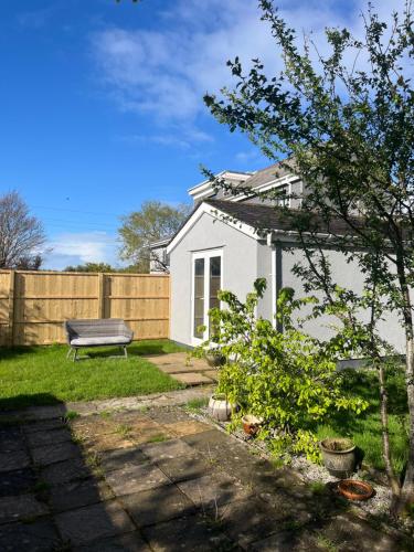 a white house with a bench in the yard at Silvermead stables Own access studios near Plymouth Life Centre FREE parking in Plymouth
