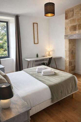 a bedroom with a bed and a desk and a window at La Salamandre - Un écrin médiéval pour vos souvenirs - Imaginez-vous, réveillé par le murmure de Sarlat, dans un appartement spacieux et chaleureux, au cœur de la Cité classée - 2 chambres - Une magie à vivre sans modération - Réservez dès maintenant ! in Sarlat-la-Canéda