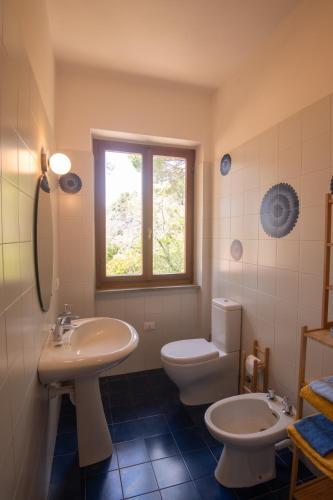 a bathroom with a sink and a toilet and a window at Villa Fornaci - Marina di Campo in Marina di Campo