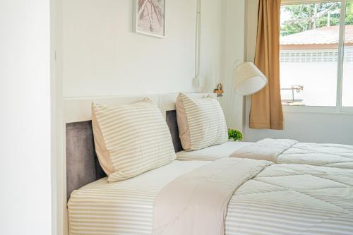 a white bed with two pillows and a window at Palai House in Ban Na Bon