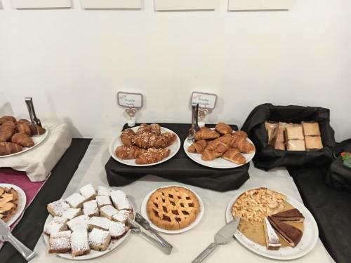 a table filled with different types of pastries and pies at venice blu hotel in Mirano