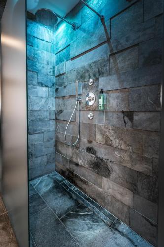 a bathroom with a shower with a stone wall at Hotel Restaurant Rosmarie in Pfelders