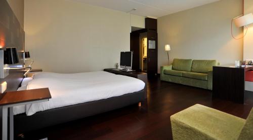 a hotel room with a bed and a couch at Golden Tulip Ampt van Nijkerk in Nijkerk