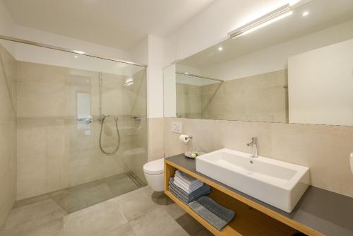 a bathroom with a sink and a toilet and a shower at Tholr - Ferienwohnungen - Tramin in Termeno
