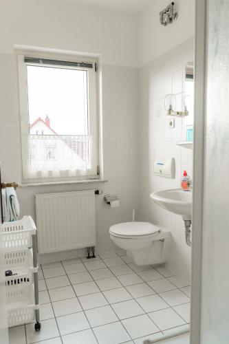 a white bathroom with a toilet and a sink at Pension Herkules in Koserow