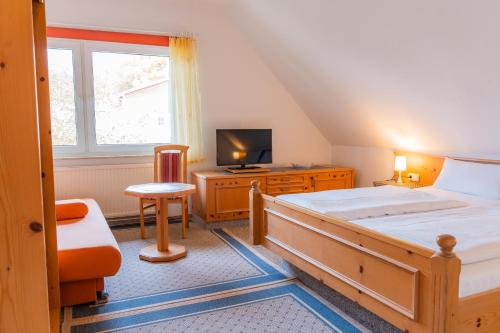 a bedroom with a bed and a tv and a window at Pension Herkules in Koserow