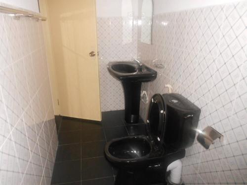 a bathroom with a black toilet and a sink at Melvila in Colombo