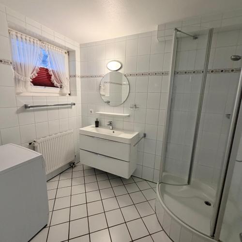a white bathroom with a sink and a shower at Kastanienhüs Apartment in Westerland