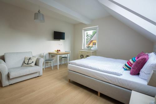a bedroom with a bed and a chair and a window at Ava Apartamenty in Niechorze