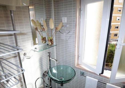 a bathroom with a glass sink and a window at Estrela Cozy Apartment in Lisbon