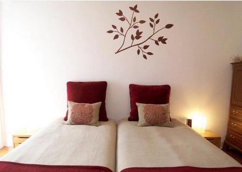 リスボンにあるEstrela Cozy Apartmentのベッドルーム1室(赤い枕のベッド2台、壁に支店付)