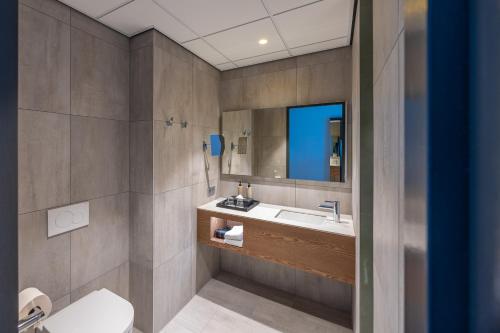 a bathroom with a sink and a mirror at Postillion Hotel Breda Biesbosch in Raamsdonksveer