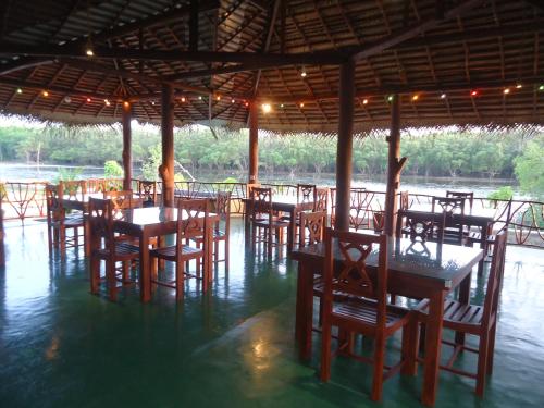 a restaurant with tables and chairs in the water at Pearl Cave Cabanas & Resturant in Tangalle