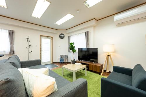 a living room with a couch and a tv at 3 Free Rental Bicycles - Free Parking - 85sqm - Up to 9 Guests - 7min to Koreatown - Japanese Lessons by Professional teacher - 自転車3台無料貸出 - 無料駐車場 - 85平米 - 定員9名 - コリアタウン徒歩7分 - Mintak Katsuyama V Residence in Osaka