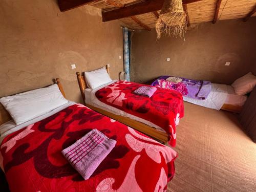two beds in a room with red and purple blankets at Café restaurante shelter calm life in Bou Dib