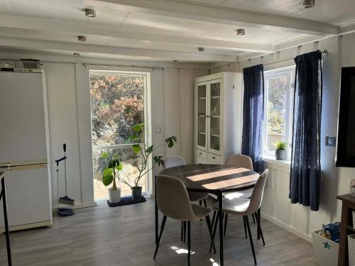 a dining room with a table and chairs and a window at Snemyr i Høvåg in Høvåg