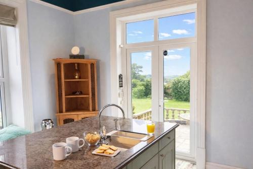 a kitchen with a counter with a sink and a window at Clevelands Country House in Wroxall