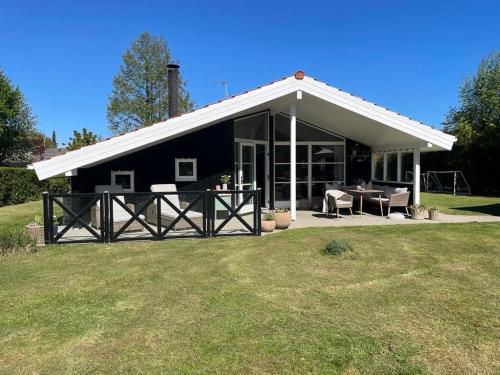 a black house with a white roof on a yard at Lækkert sommerhus i gåafstand til by og strand in Bøtø By
