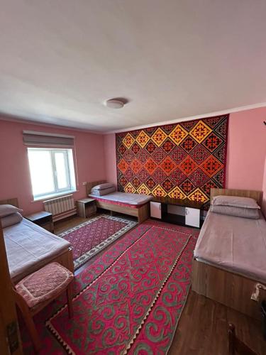 a room with two beds and a red rug at Tumar guest house, Kochkor in Kochkorka
