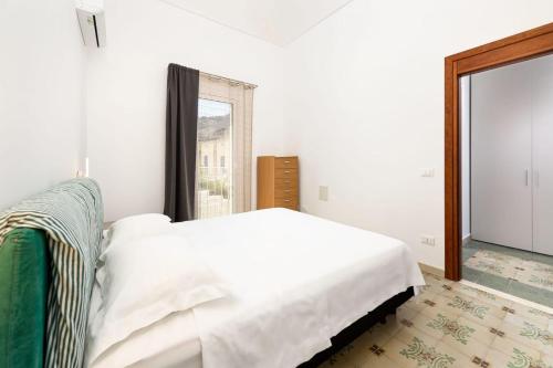 a white bedroom with a bed and a window at Sinedda Sole in San Vito lo Capo