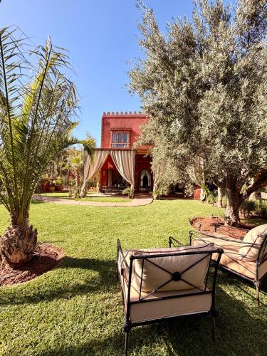 a park bench sitting in the grass in front of a house at Villa Dar Al Hayat in Marrakesh