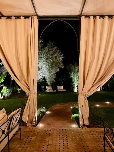 a tent with curtains in a garden at night at Villa Dar Al Hayat in Marrakesh