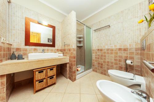 a bathroom with a sink and a toilet and a mirror at Villa Solara - com piscina aquecível e BBQ em Carvoeiro in Carvoeiro
