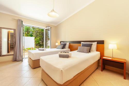 two beds in a room with a window at Villa Solara - com piscina aquecível e BBQ em Carvoeiro in Carvoeiro