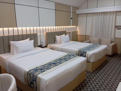 a hotel room with two beds and a chair at Fiona Luxury Resort in Gazipur