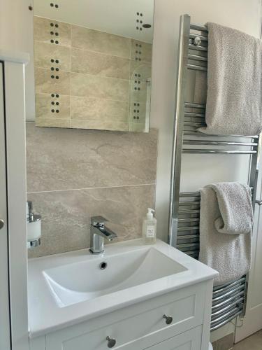 a bathroom with a white sink and a mirror at The Meadows, OXTED in Tandridge