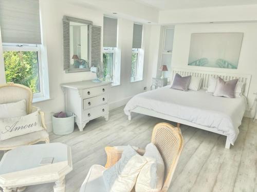 a white bedroom with a bed and a chair at The Meadows, OXTED in Tandridge