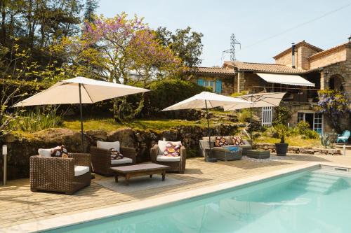 a pool with chairs and umbrellas next to a house at Idyllic French farmhouse in Les Assions