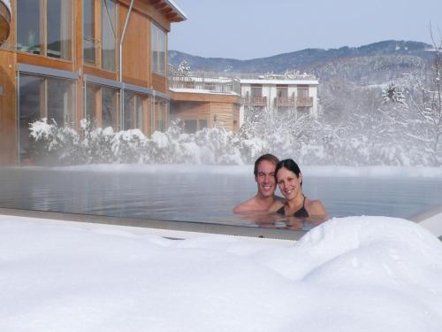 a man and woman in a hot tub in the snow at RETTER Bio-Natur-Resort in Pöllauberg