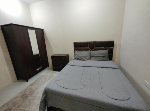 a small bedroom with a bed and a wooden cabinet at comfort stay 205 in Al Ain