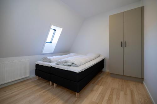 a small bedroom with a bed and a window at Lønstrup Apartments, Klitrose in Lønstrup