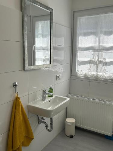a white bathroom with a sink and a mirror at Fachwerkjuwel im Bergischen in Remscheid