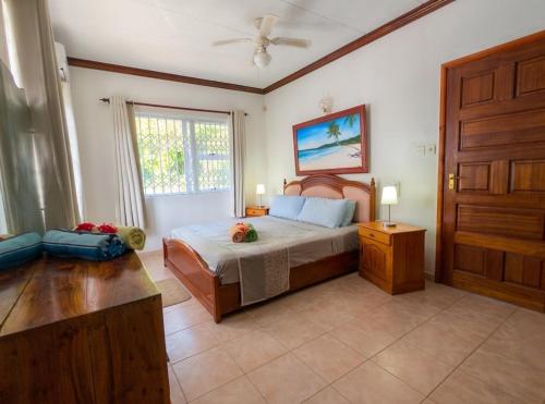 a bedroom with a bed and a window and a door at Villa Bel Age Seychelles in Anse Royale