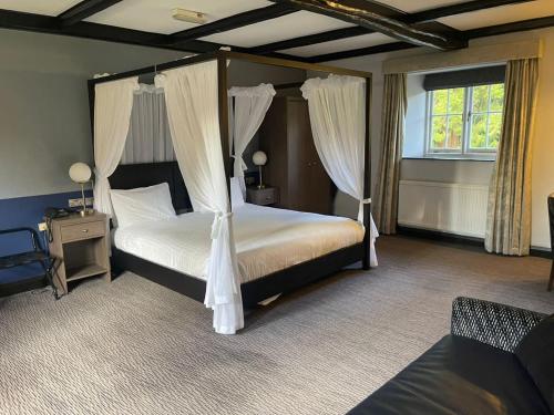 a bedroom with a four poster bed with curtains at Cwrt Bleddyn Hotel & Spa in Usk